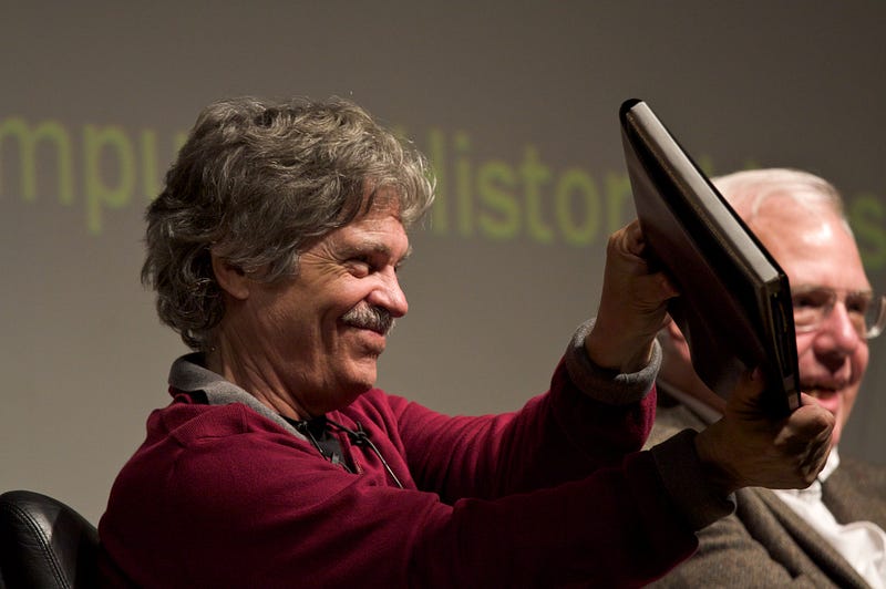 Alan Kay holding a mockup of the Dynabook
